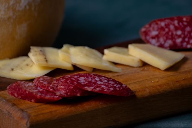 Rodajas de salame y láminas de queso sobre una tabla de madera